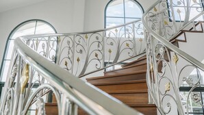Una escalera de caracol con barandillas de metal ornamentadas y peldaños de madera.