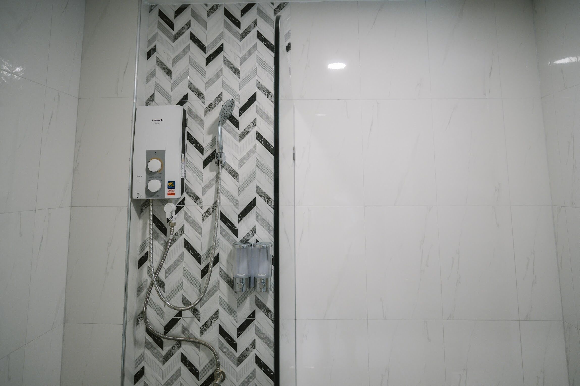 Une salle de bain avec une douche, un radiateur fixé au mur et un pare-chocs en carreaux disposés en motif chevrons.