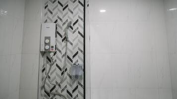 Une salle de bain avec une douche, un radiateur fixé au mur et un pare-chocs en carreaux disposés en motif chevrons.
