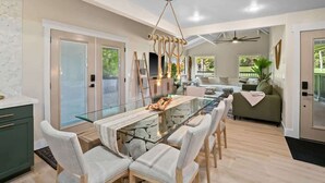 A modern kitchen with a glass dining table, a ceiling fan, and a view of the outdoors.