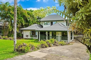A two-story house with a porch, surrounded by tropical vegetation. - Kauai Mermaid Queen Sanctuary - Sleeps 16 - A/C! (Princeville)