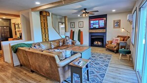 A living room with a sofa, a coffee table, a fireplace, and a TV mounted on the wall. - Spacious 3BR chalet in Fleetwood, NC, perfect for family gatherings, sleeps 10. (Fleetwood)