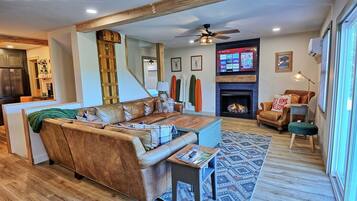 A living room with a sofa, a coffee table, a fireplace, and a TV mounted on the wall.