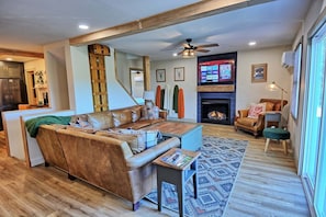 A living room with a sofa, a coffee table, a fireplace, and a TV mounted on the wall.