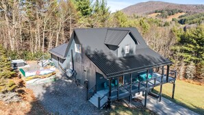 A large house with a covered porch and a hot tub in the backyard. - Spacious 3BR chalet in Fleetwood, NC, perfect for family gatherings, sleeps 10. (Fleetwood)