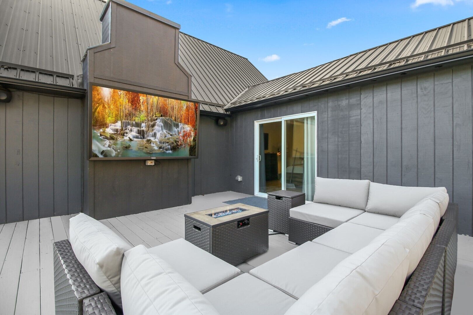 An outdoor patio with a sofa, a coffee table, and a fireplace.