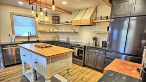 A kitchen with a central island, wooden cabinets, a stainless steel refrigerator, and a window with blinds. - Spacious 3BR chalet in Fleetwood, NC, perfect for family gatherings, sleeps 10. (Fleetwood)