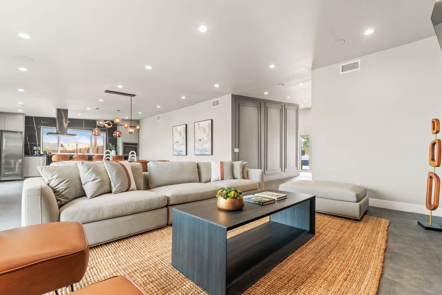 Un salon moderne avec un canapé d’angle, une table basse et un coin repas à l’arrière-plan.