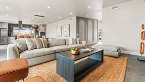 Una sala de estar moderna con un sofá seccional, una mesa de centro y un área de comedor al fondo.