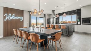 Una cocina moderna con una isla grande, un comedor con sillas y un letrero de neón.