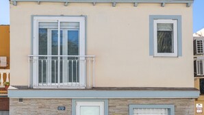 Un edificio de dos pisos con fachada de piedra, un balcón y una puerta con un panel de vidrio que presenta un diseño de oso.