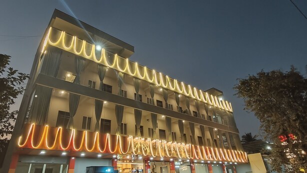 Un hôtel à plusieurs étages dont la façade est ornée de motifs ondulés illuminés, doté de grandes fenêtres et abritant un restaurant au rez-de-chaussée.