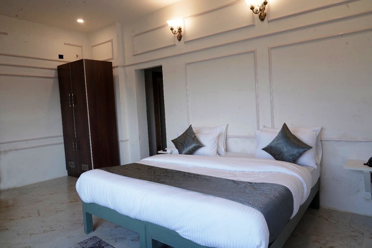 A bedroom with a bed, bedside table, wardrobe, and wall-mounted light fixtures.