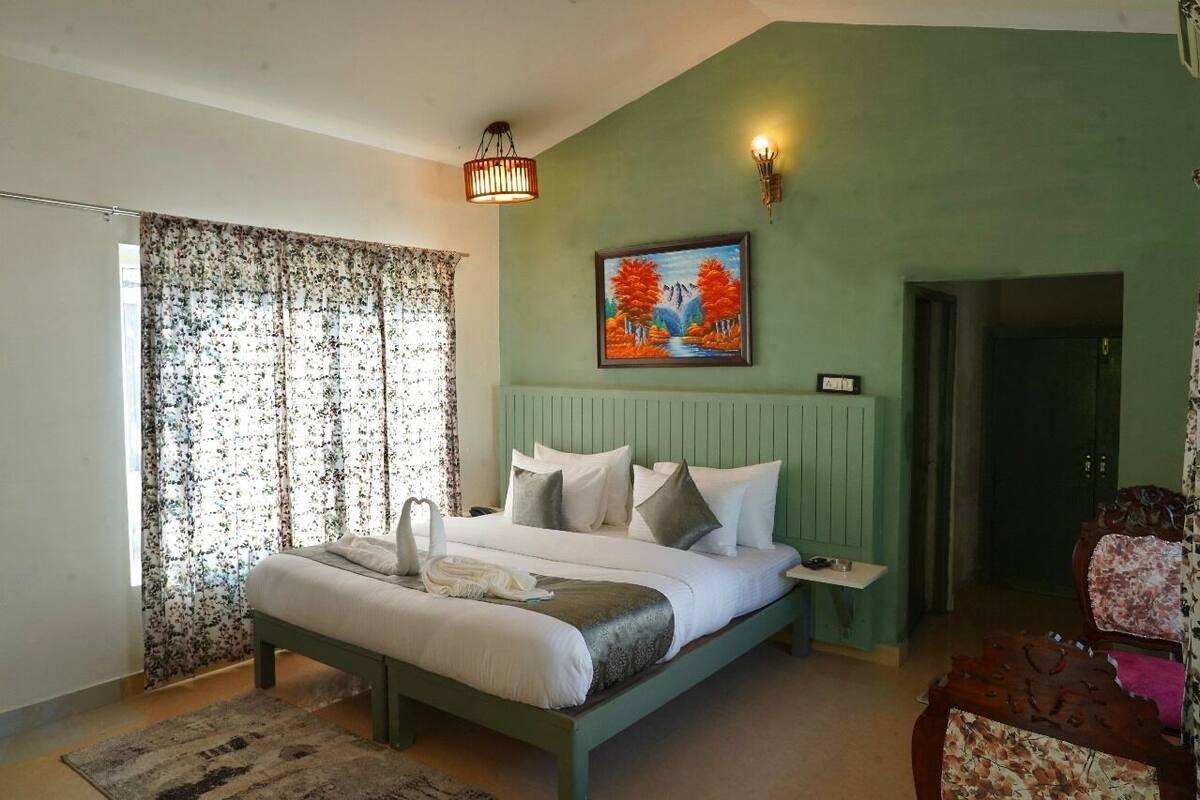 A bedroom with a bed, a painting, a nightstand, and a chair.