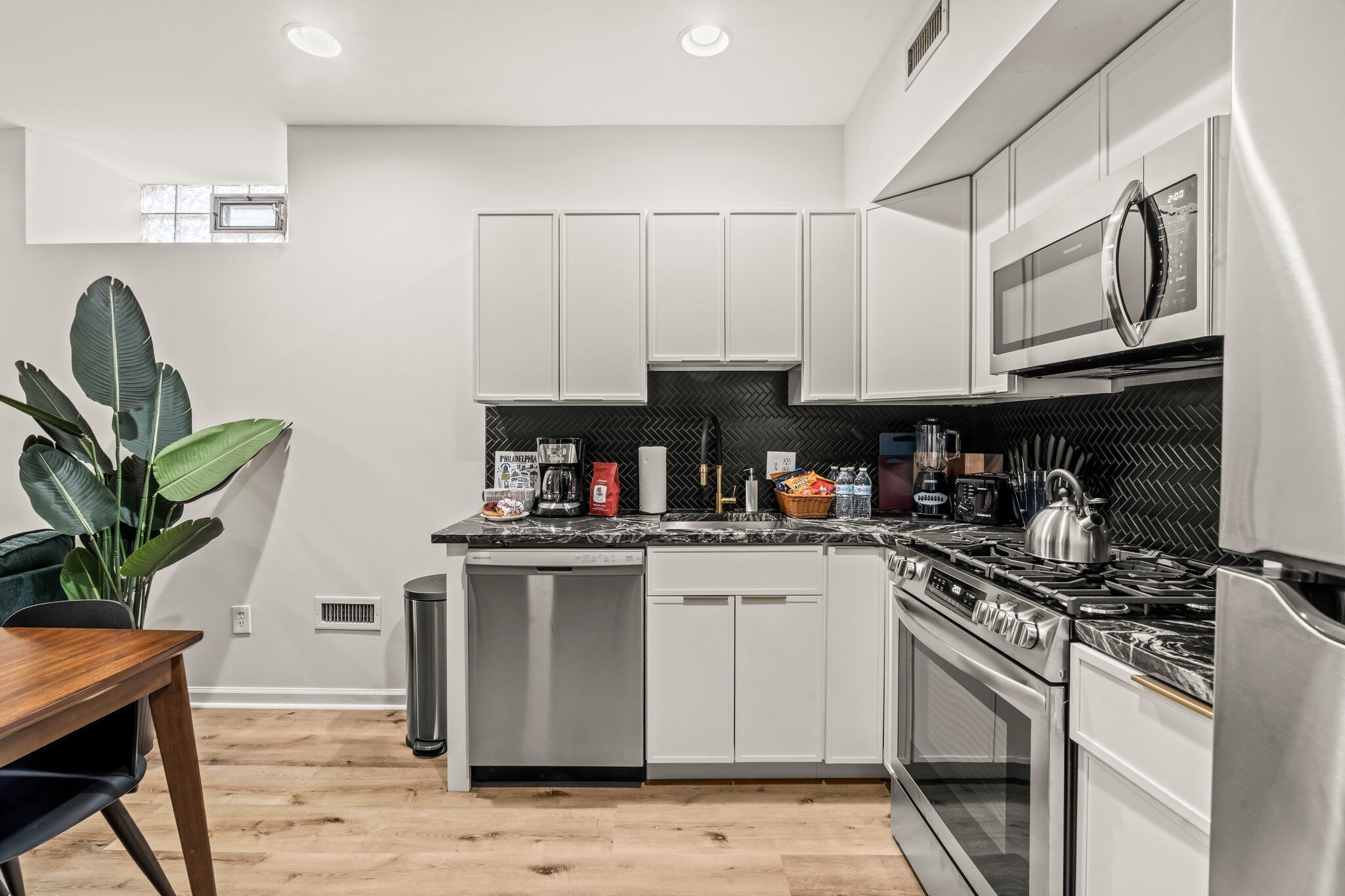 A modern kitchen with white cabinets, a stainless steel stove, and a microwave.