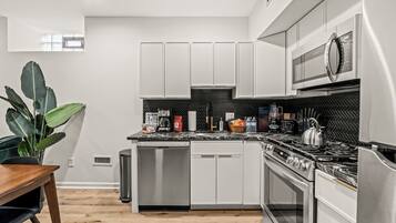 A modern kitchen with white cabinets, a stainless steel stove, and a microwave.
