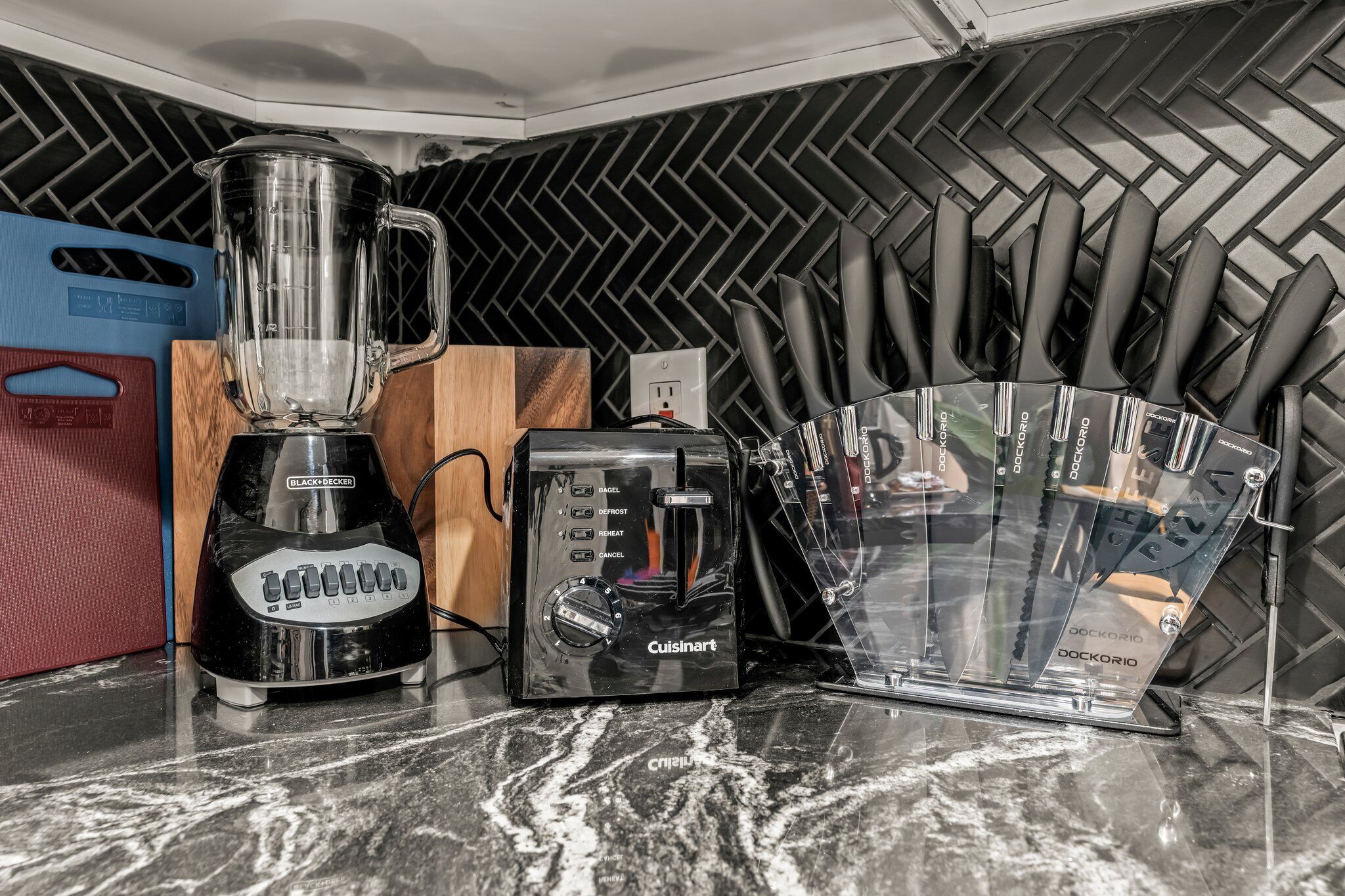 A kitchen counter with a Black & Decker blender, a Cuisinart toaster, and a Dockorio knife block.