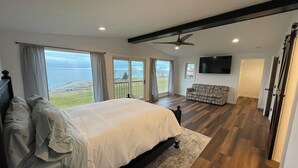 Een slaapkamer met een groot bed, een plafondventilator, een televisie en uitzicht op de omgeving.