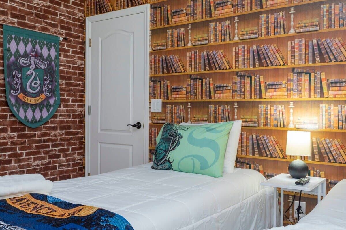 Une pièce avec un mur en briques, une bibliothèque remplie de livres, une porte et un lit avec un oreiller.