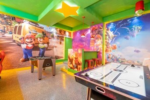 A room with a foosball table, a Mario-themed mural, and a star ceiling.