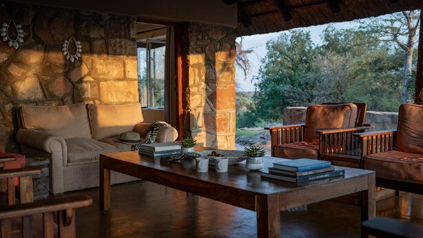 Un intérieur chaleureux avec une cheminée en pierre, des sièges confortables et une vue sur l’extérieur.