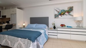 Un dormitorio con cama, mesita de noche, lámpara y un cuadro en la pared.