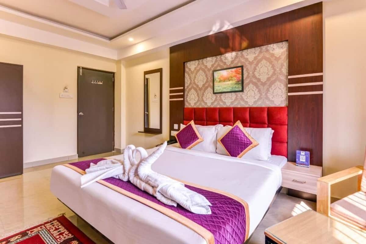 Ein Hotelzimmer mit einem großen Bett, einem roten, mit Stoff bezogenen Kopfteil, einer Holz-Akzentwand und einem gerahmten Bild.