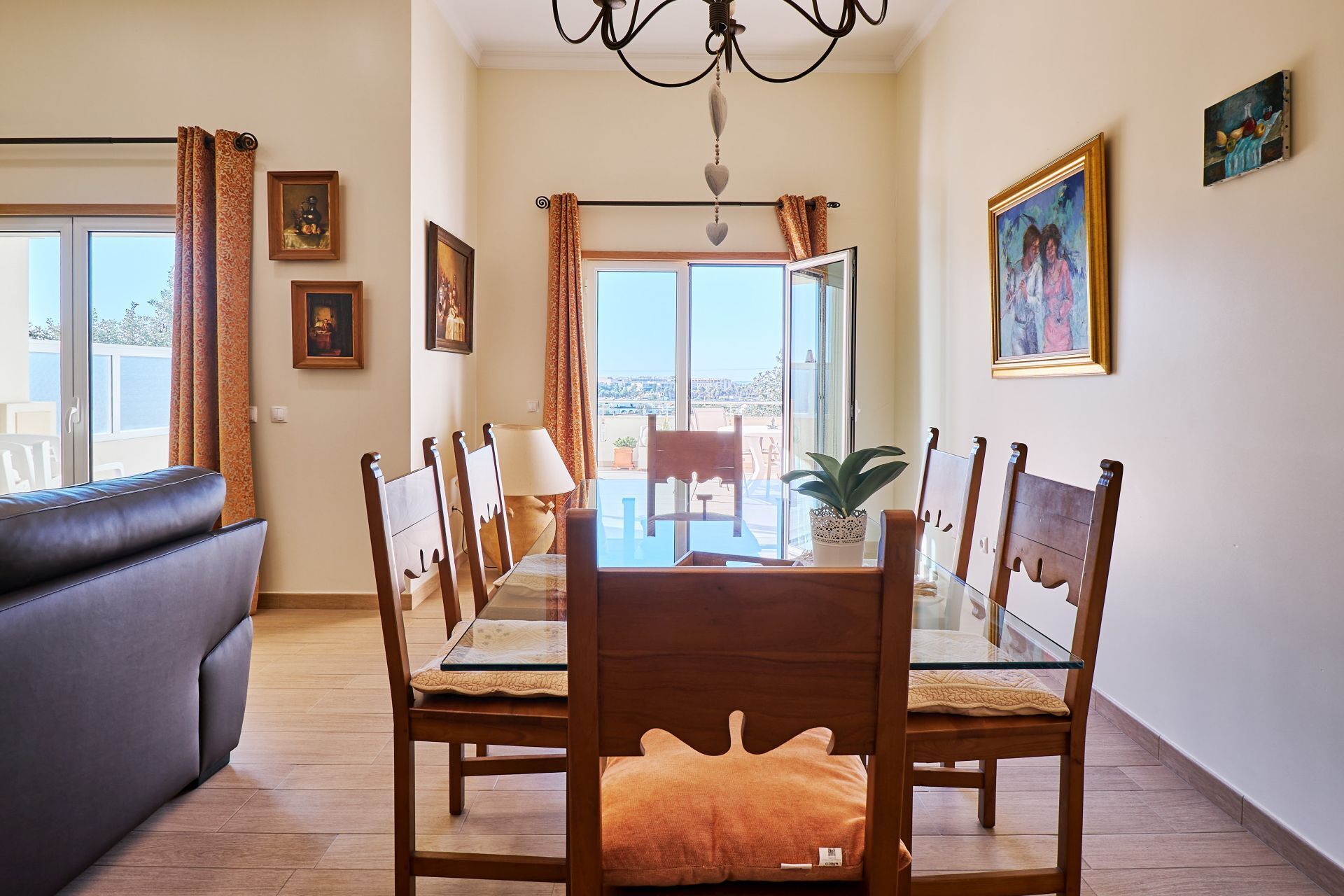 Zona pranzo con tavolo in vetro, sedie in legno e vista sull'esterno tramite ampie finestre.