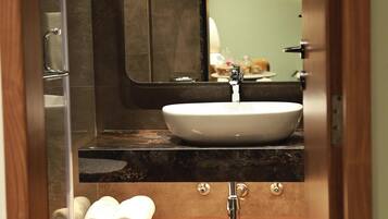 Une salle de bain équipée d’un lavabo, d’un miroir, d’un porte-serviettes et d’une zone douche.
