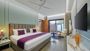 Una habitación de hotel moderna con una cama grande, ventilador de techo, televisor y vistas al exterior.