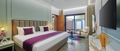 Een moderne hotelkamer met een groot bed, een plafondventilator, een televisie en uitzicht op de omgeving.