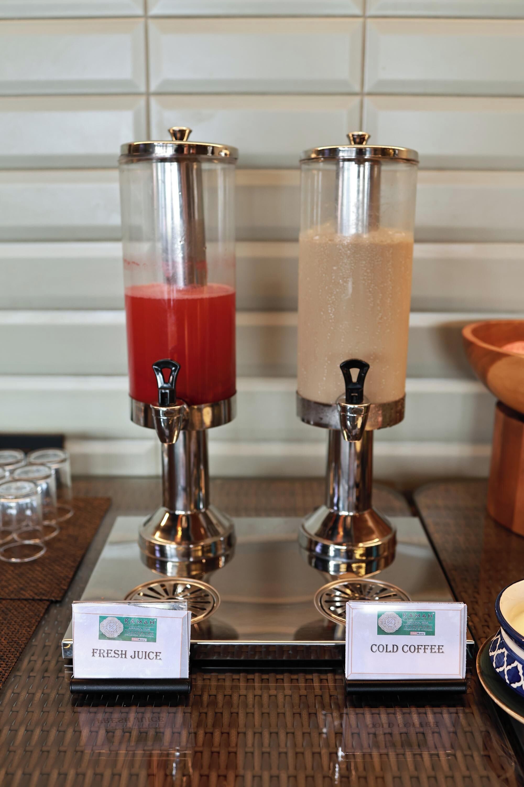 Deux distributeurs de boissons, placés sur un plateau, avec les étiquettes « Jus frais » et « Café froid ».