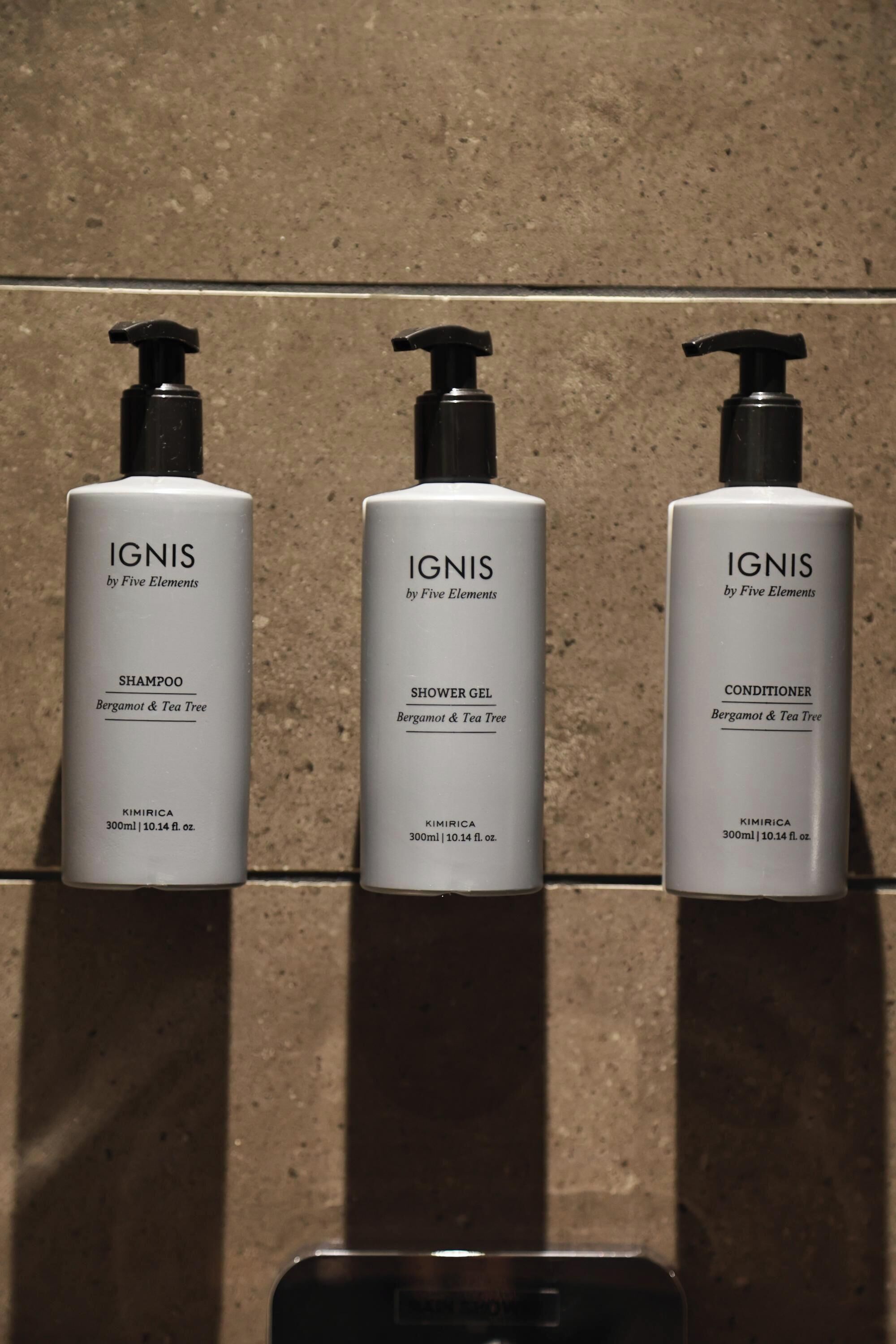 Tres botellas de productos IGNIS de Five Elements: champú, gel de ducha y acondicionador, cada uno con dosificador tipo bomba.