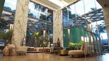 A spacious lobby with marble walls, large windows, and modern furniture.