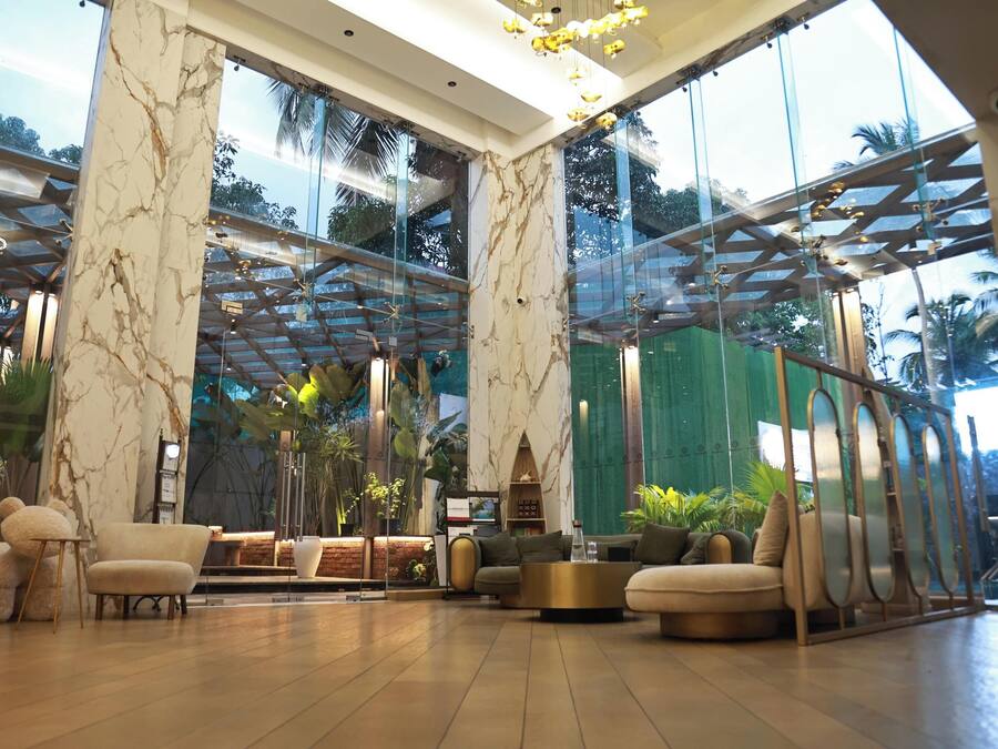 Un vestíbulo amplio con paredes de mármol, ventanas grandes y muebles modernos.
