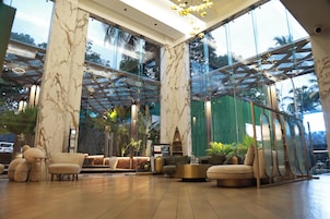 Un vestíbulo amplio con paredes de mármol, ventanas grandes y muebles modernos.