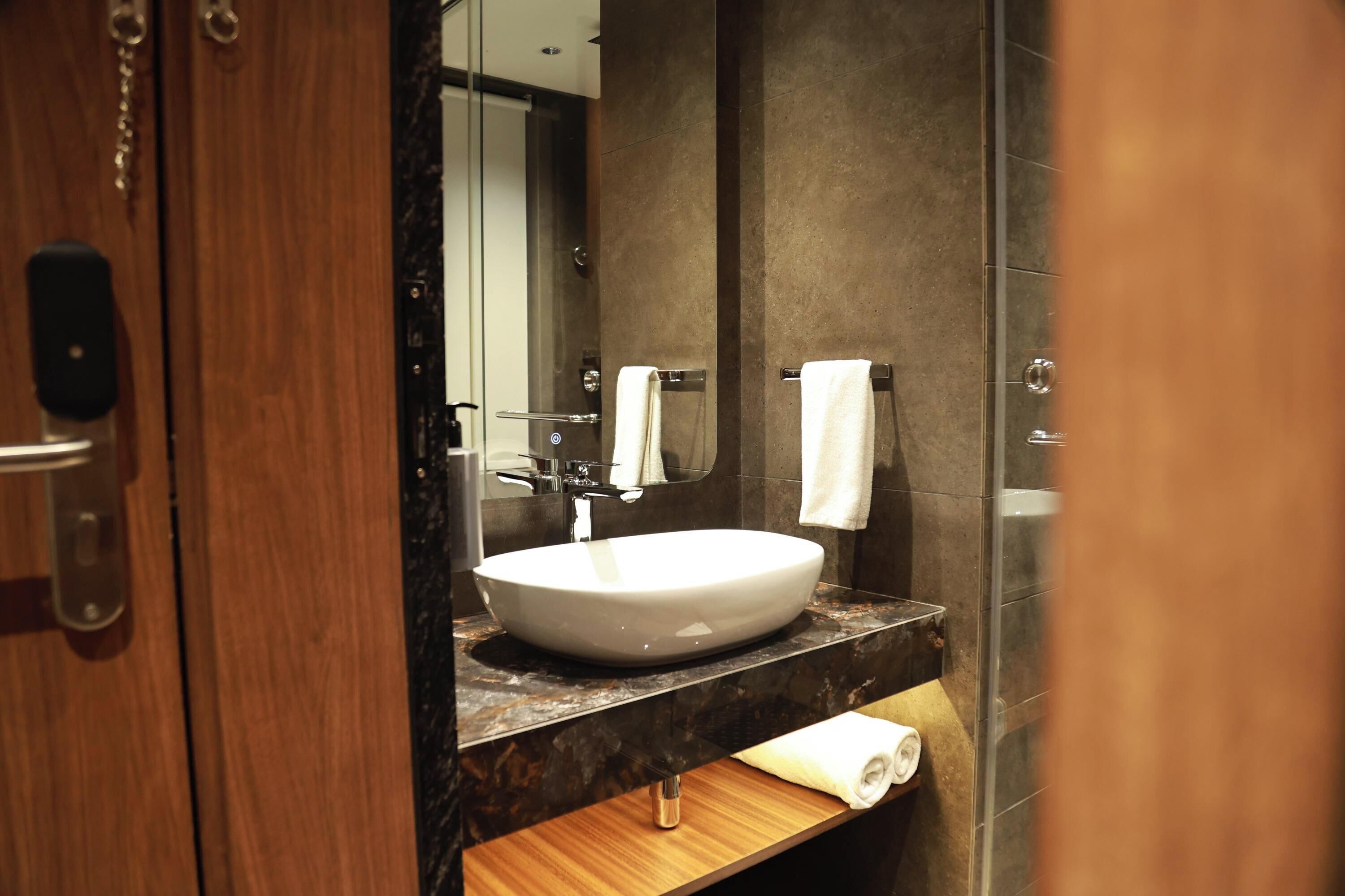 A bathroom with a white sink, a mirror, and a towel rack.