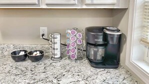 A kitchen with a coffee maker, a coffee pod holder, and two bowls on the counter. - Stylish 2BR in Decatur | Big Deck • Pets OK • Quiet Area (Decatur)