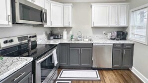 A kitchen with white cabinets, a stainless steel microwave, a gas stove, and a dishwasher. - Stylish 2BR in Decatur | Big Deck • Pets OK • Quiet Area (Decatur)