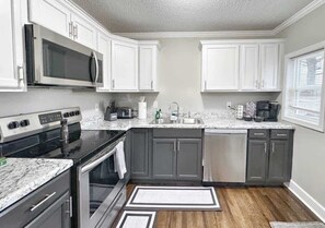 A kitchen with white cabinets, a stainless steel microwave, a gas stove, and a dishwasher.