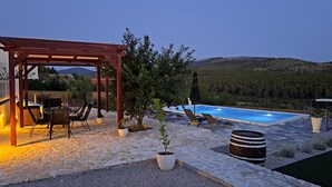 A stone patio with a pool, lounge chairs, a pergola, and potted plants. - Stunning home in Sibenik (Sibenik)