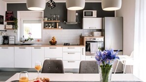 A modern kitchen with white cabinets, a built-in oven, and a dining area with a table set for two. - Stunning home in Sibenik (Sibenik)