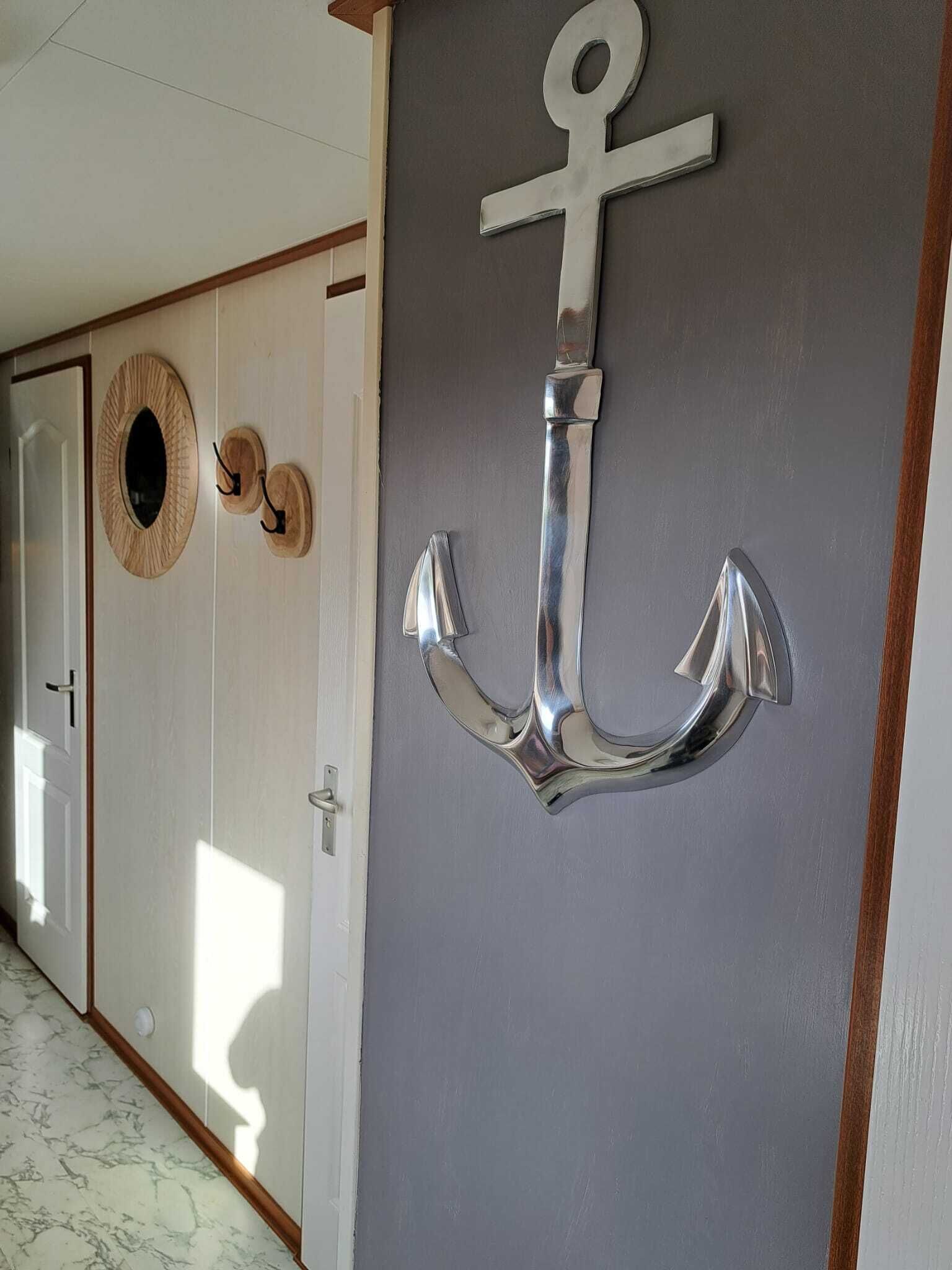 Ein Zimmer mit grauer Wand, einer Holztür und einer großen Anker-Dekoration.