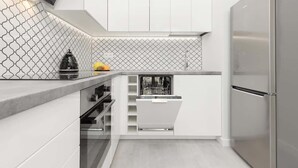 Una cocina moderna con armarios blancos, un refrigerador de acero inoxidable y un salpicadero con diseño.