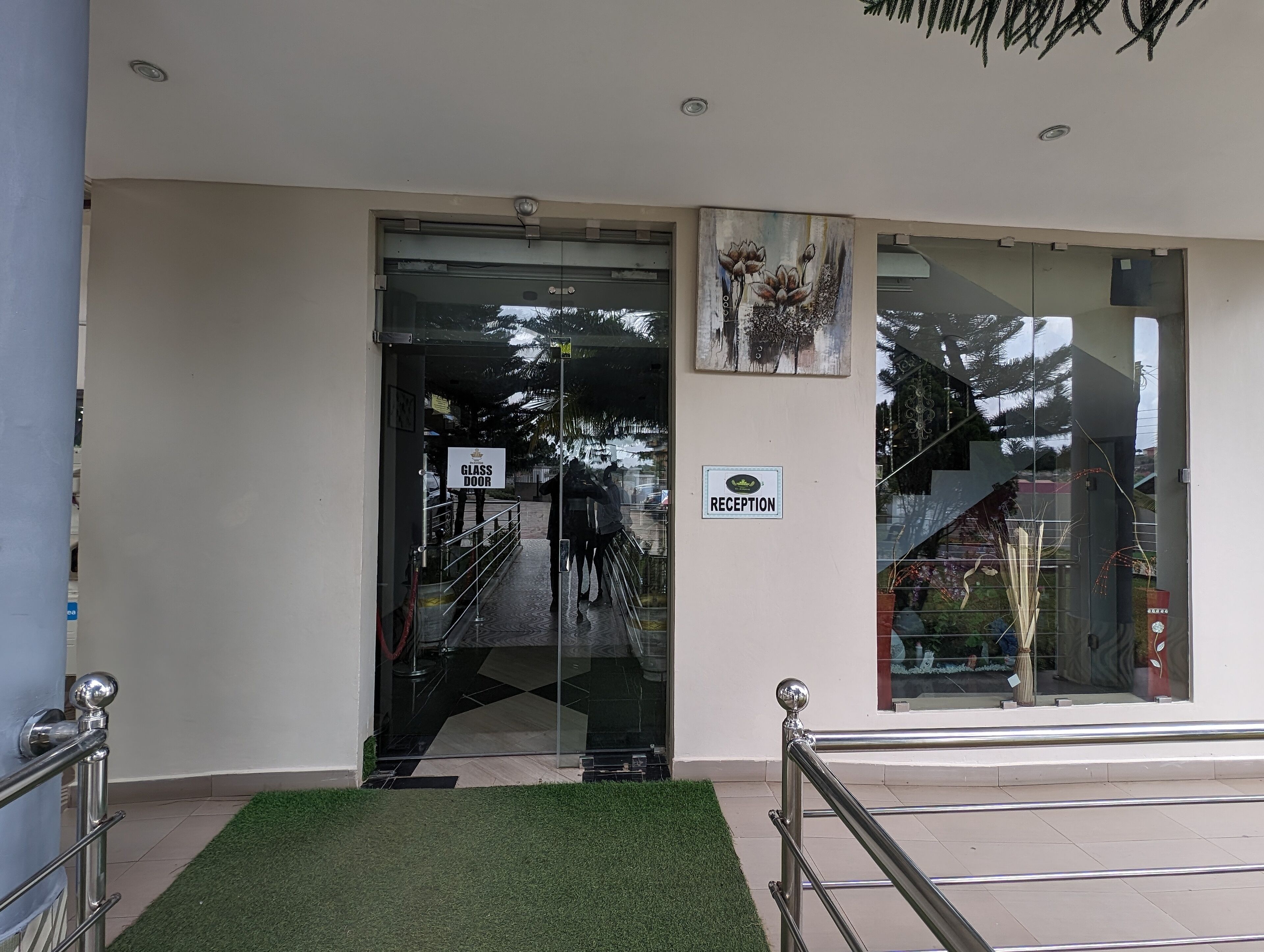 A reception area with a glass door, a reception sign, and a framed artwork on the wall.