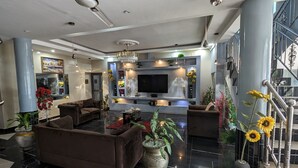 Een moderne woonkamer met een grote flatscreen televisie, comfortabele zitplaatsen en decoratieve planten.