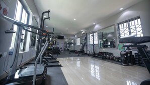 Een fitnessruimte met loopbanden, gewichten en trainingsapparatuur.