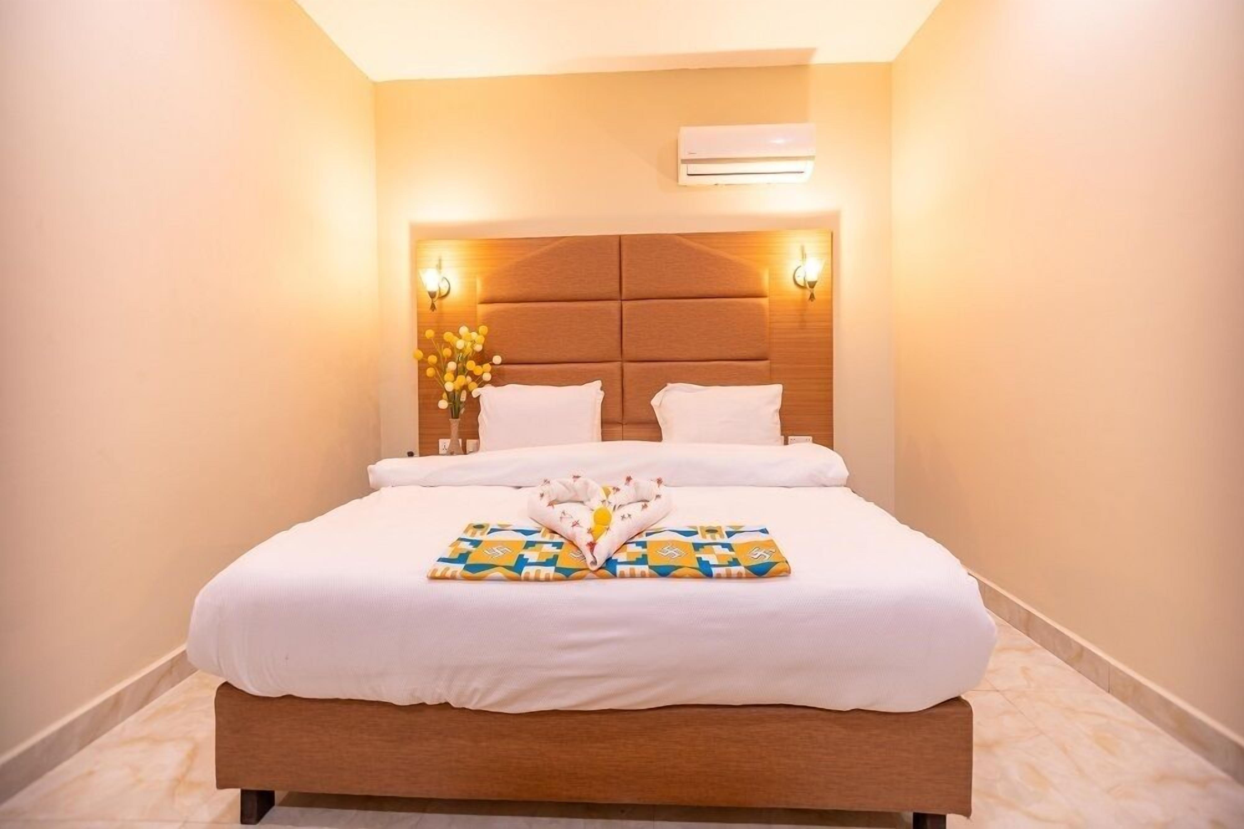 A neatly made bed with white linens and a decorative towel arrangement.
