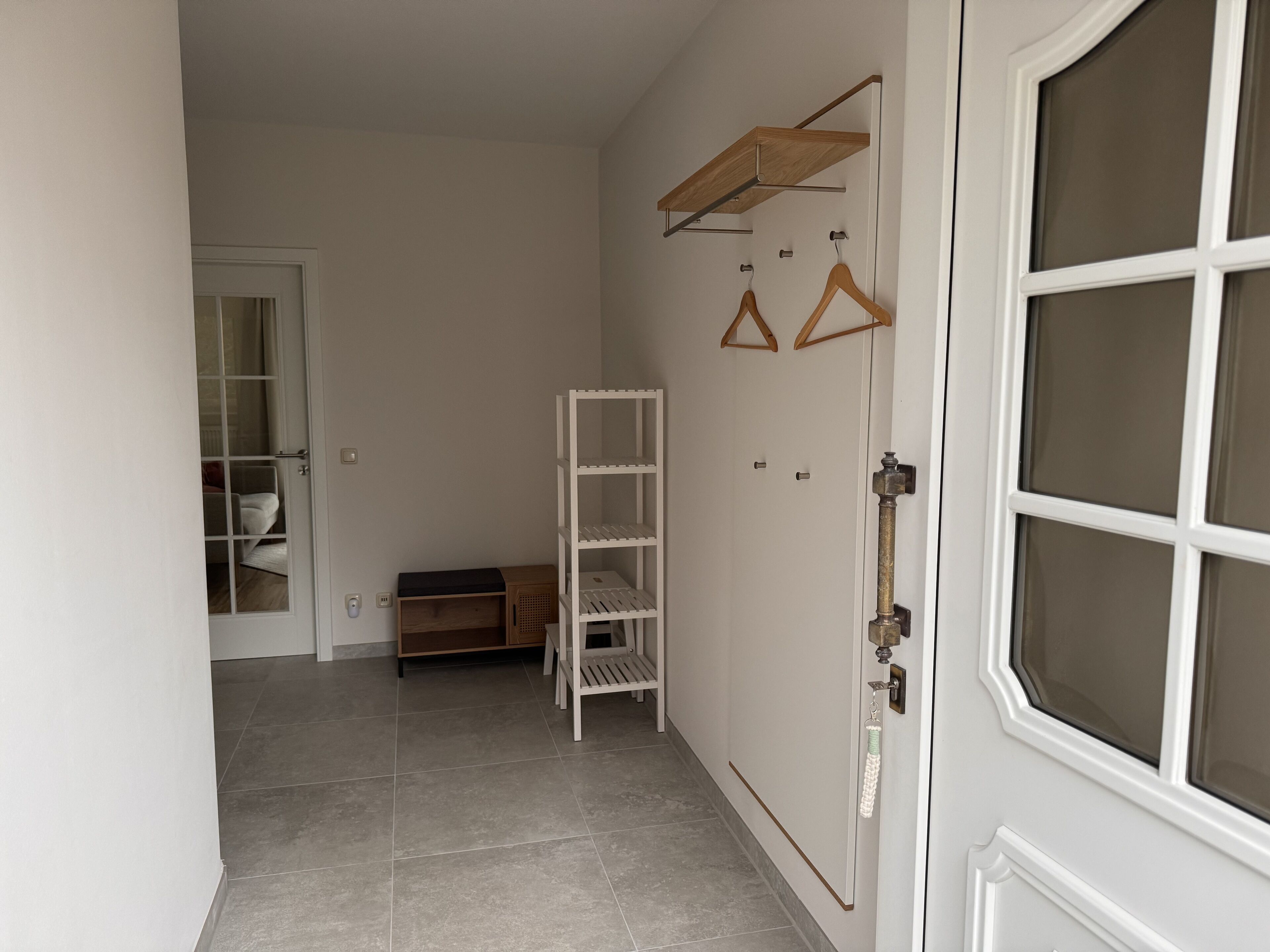 A hallway with a white door, a white shelf unit, and a wooden bench.