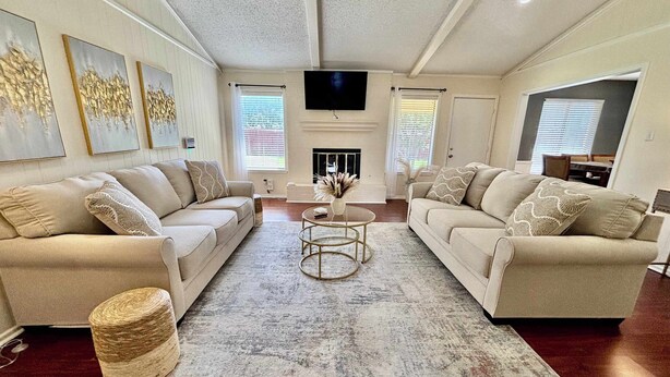 A living room with two beige sofas, a coffee table, and a fireplace. - Blue Jay's Magnolia - 3BR 2BA - Family Friendly (Lubbock)